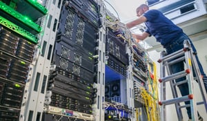man installing network cabling in office server room