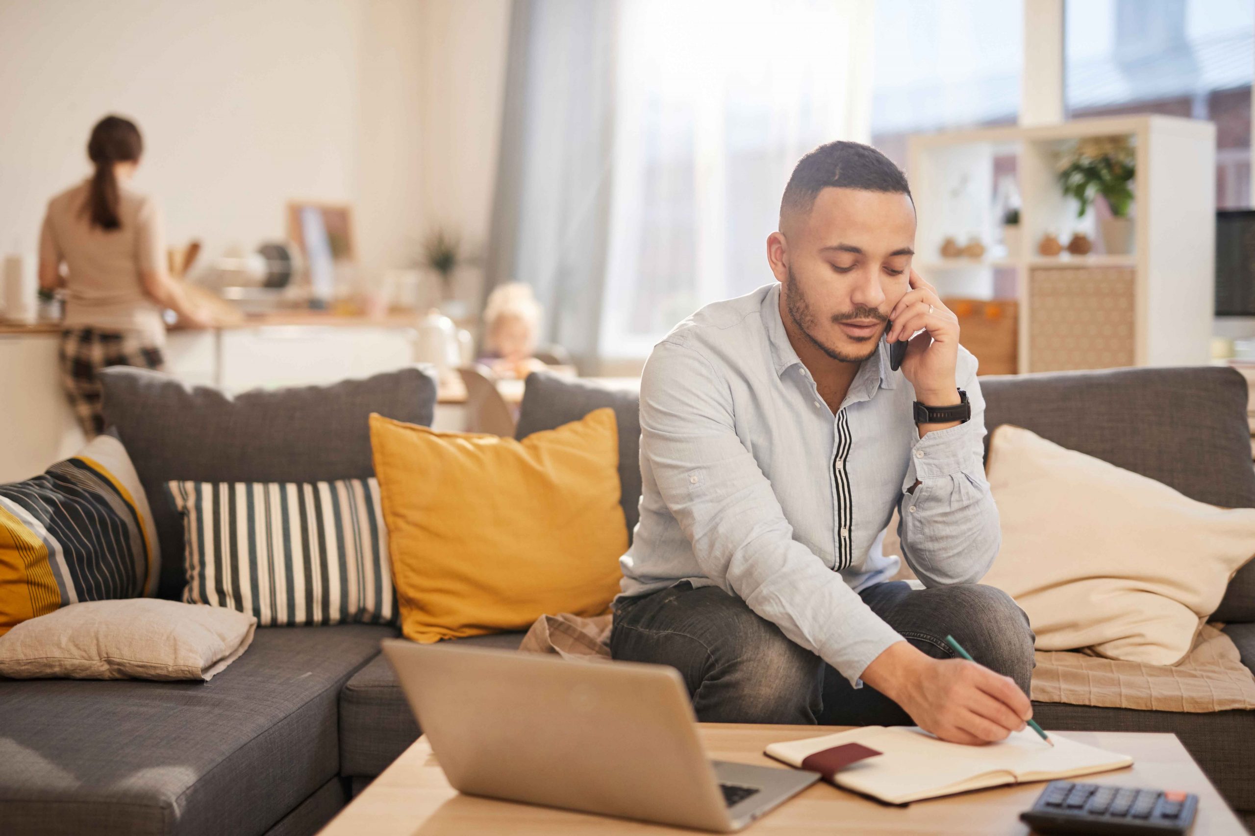 man talking on cellphone while taking notes