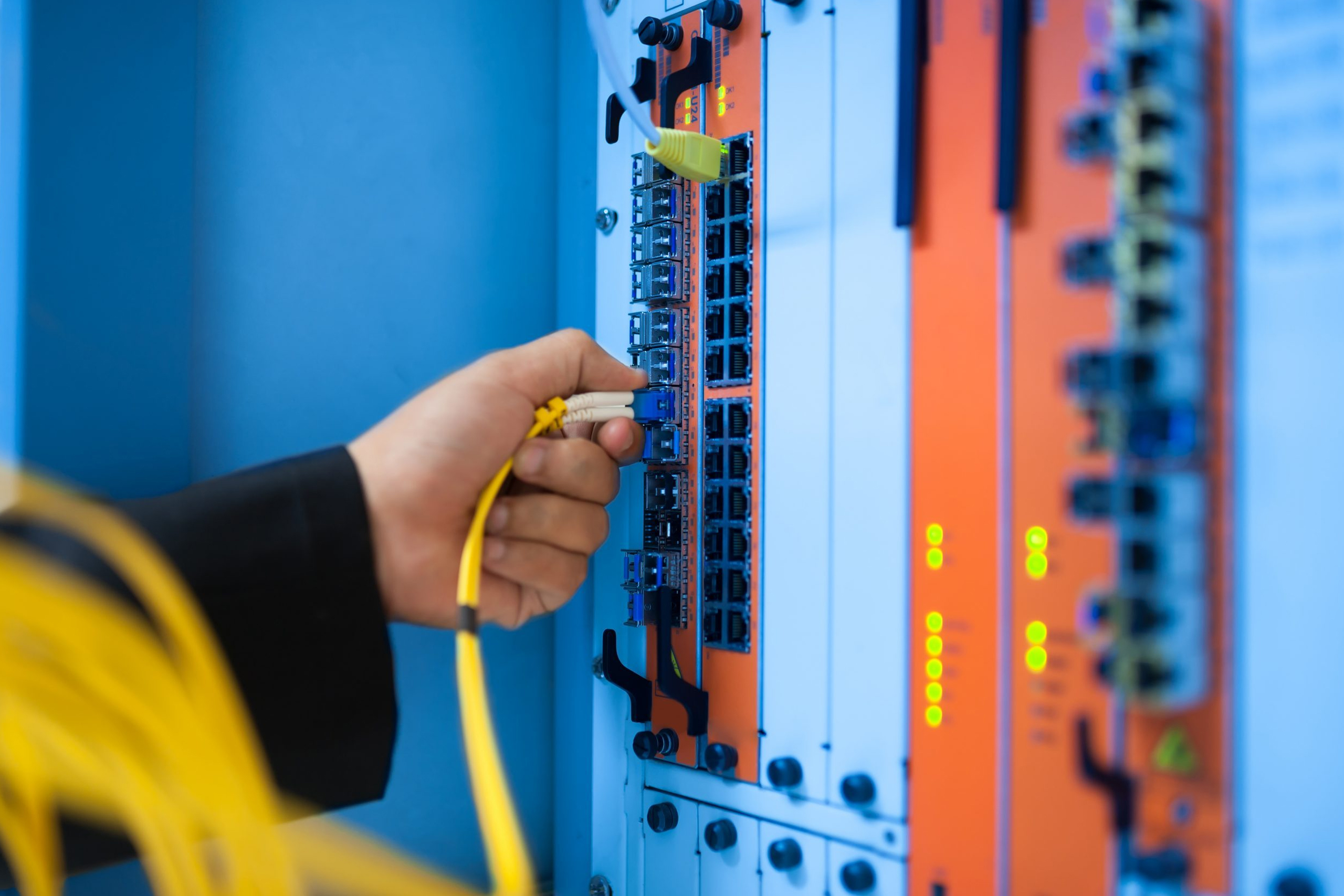 Worker plugging ethernetc cable into installed switch