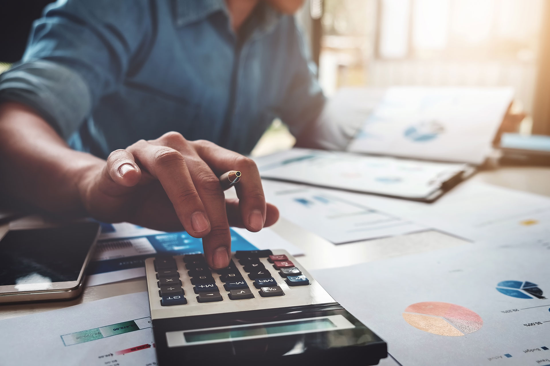 man using calculator while looking at financial documents