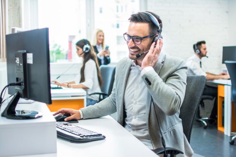 man on phone support and using computer