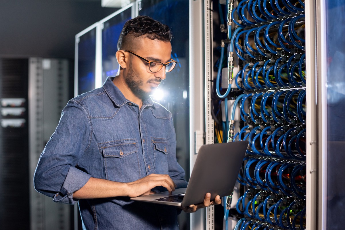 man inspecting network cables with laptop