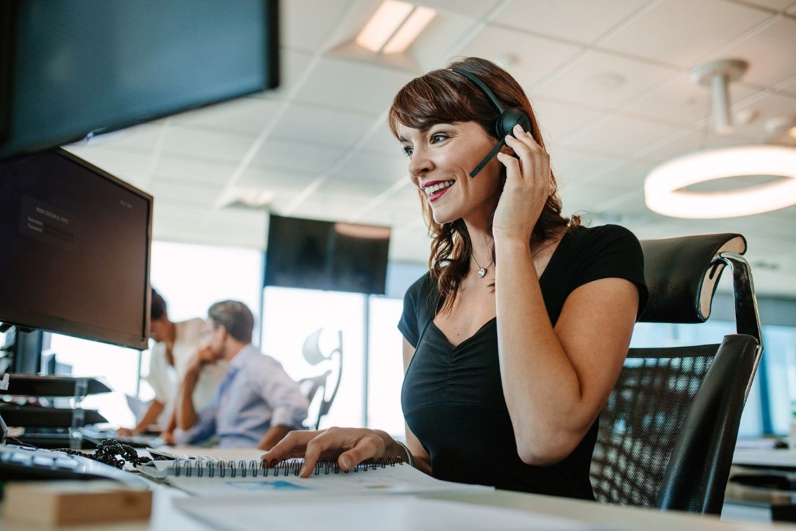 female support agent with headset in front of computer