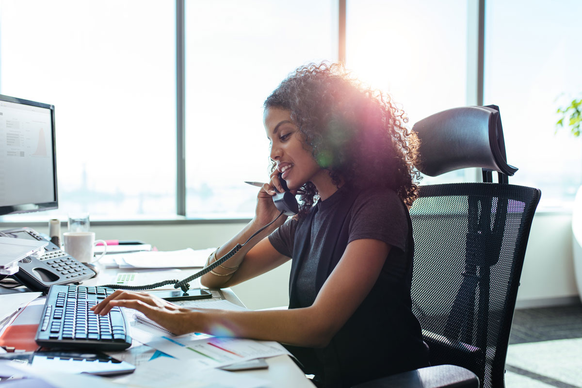 woman on phone typing on keyboard at office