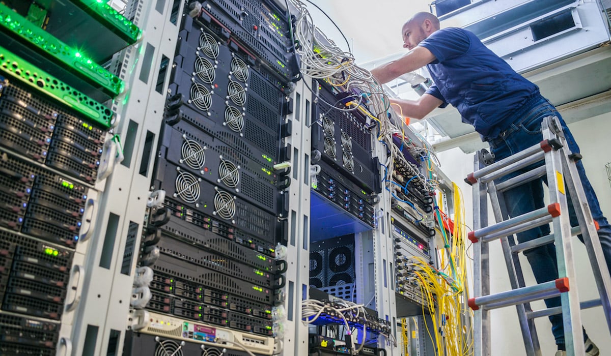 man installing network cabling in office server room