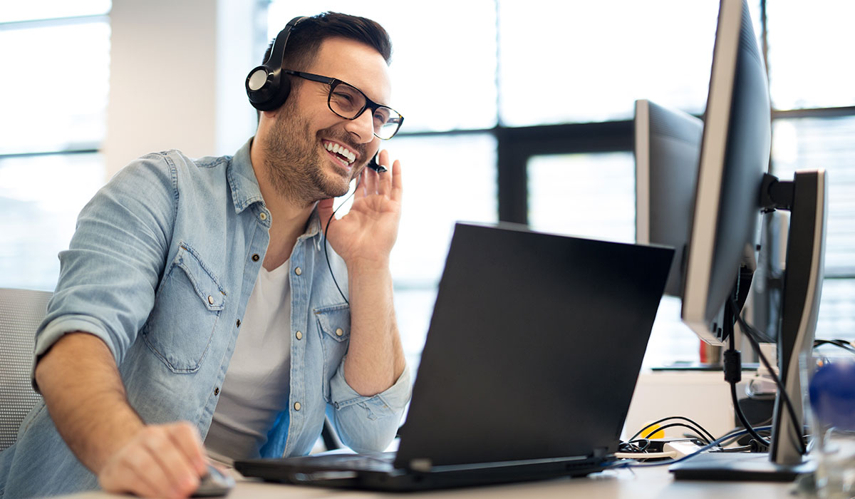 man smiling while talking on headset at the office