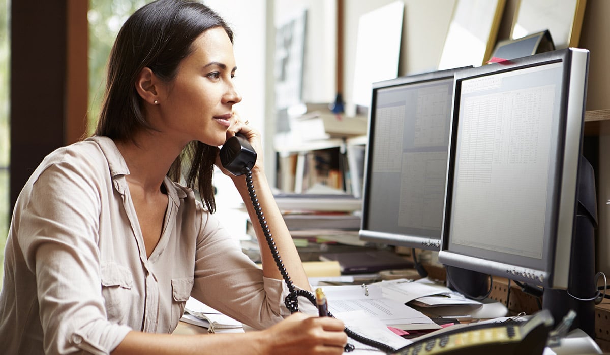 woman talking on phone and using computer