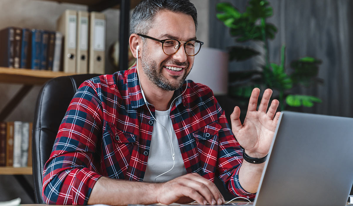 man waving at laptop on conference call