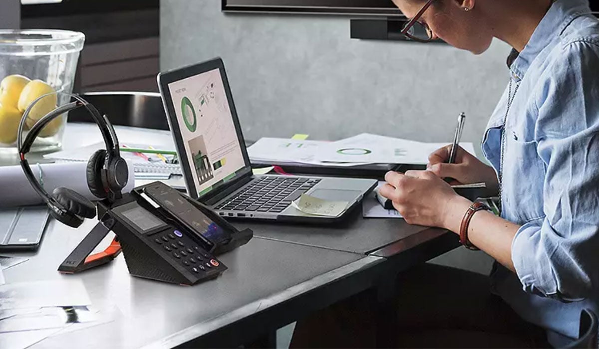 woman working from home with polycom vvx phone on desk